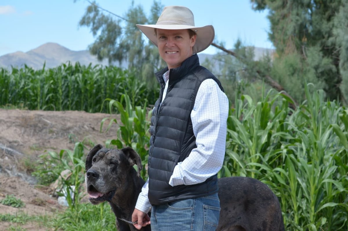 Alfredo, productor lechero de DataMoo, en el rancho con su perro frente al maíz